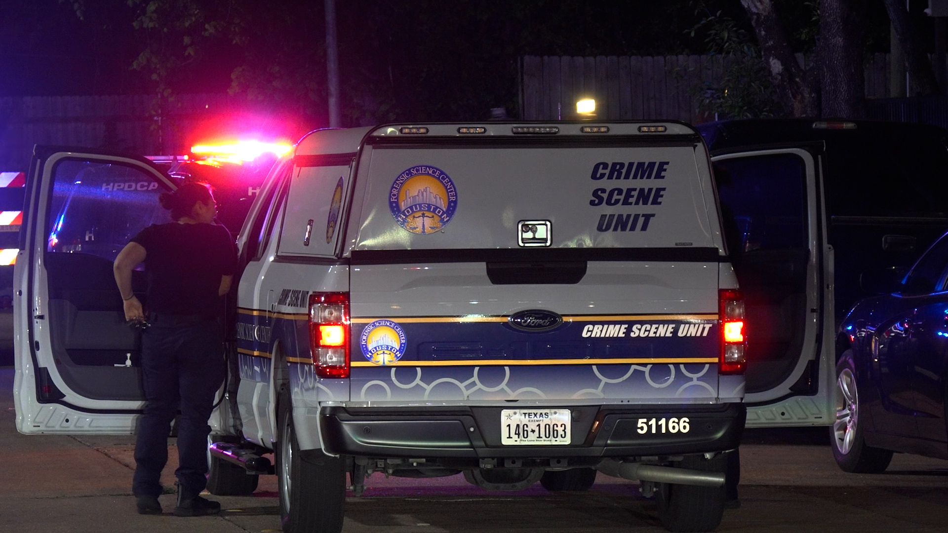 Houston Crime Scene Unit van with open rear door and a person standing beside it at night, red and blue emergency lights flashing