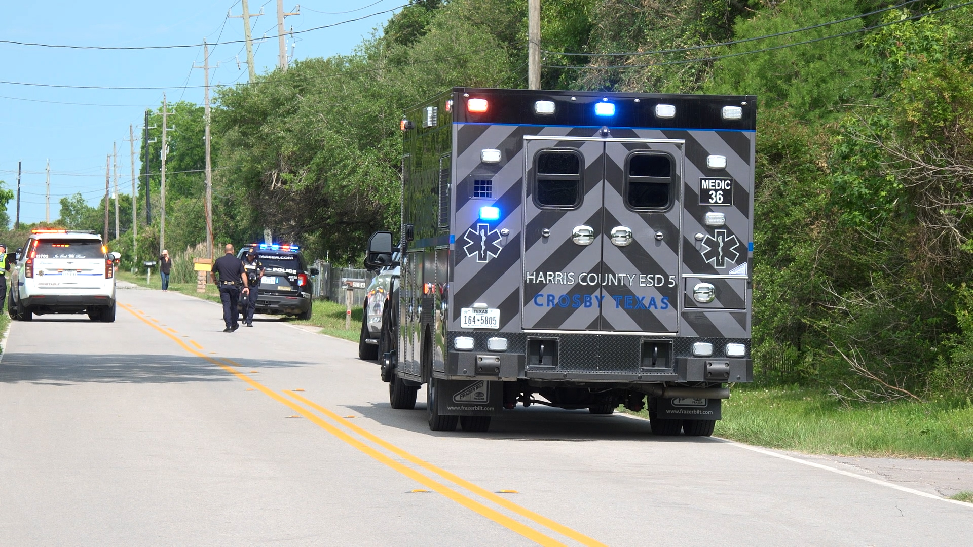 Emergency response vehicles on a suburban street with cops and an ambulance, blue and red lights flashing, Crosby, Texas.