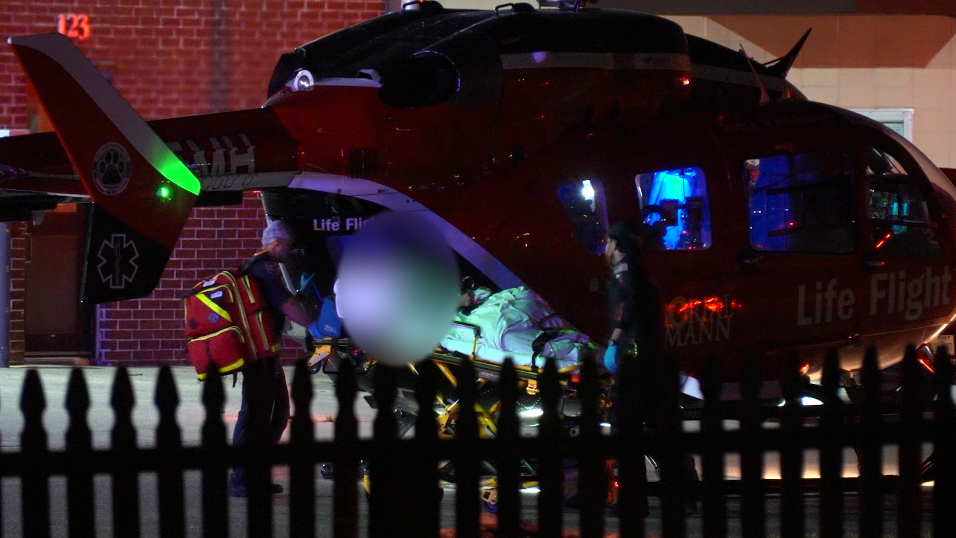 Red Life Flight helicopter at night with medical crew loading a patient on a stretcher