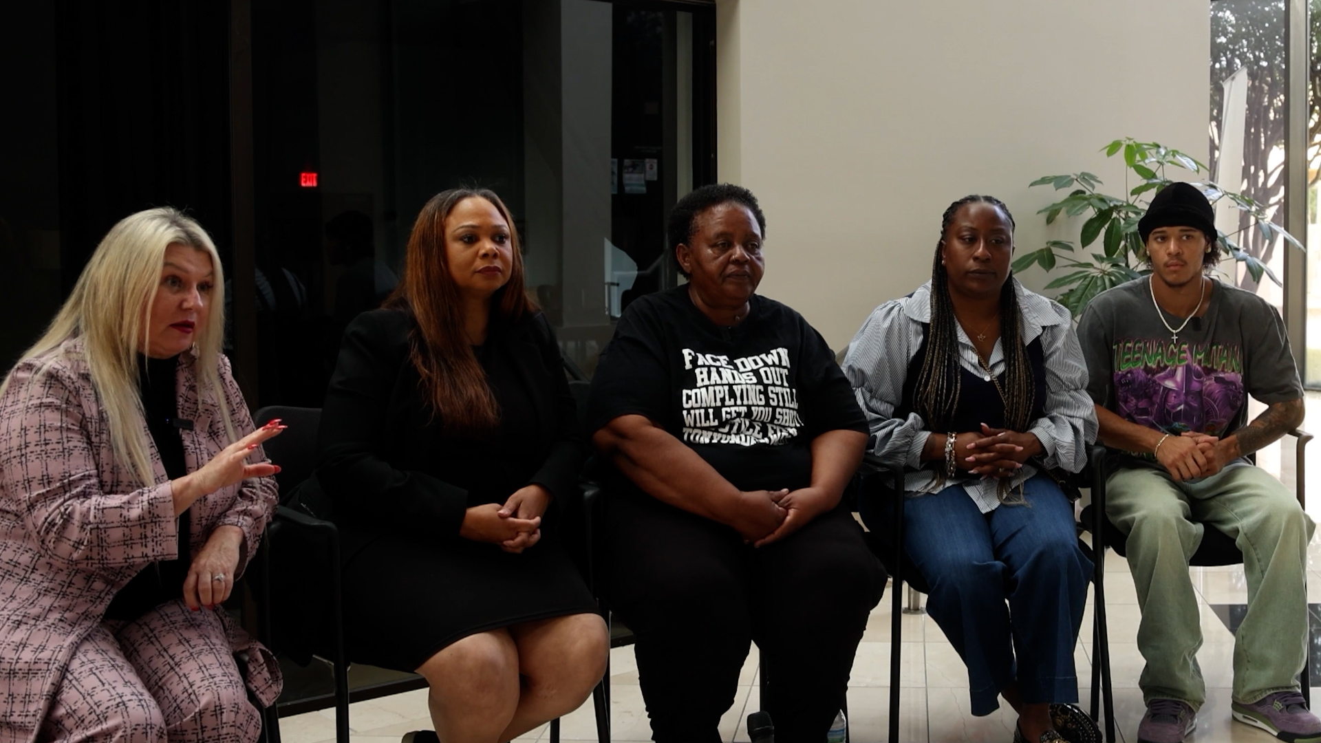 Five diverse people seated in a row indoors, appearing to participate in a panel discussion.