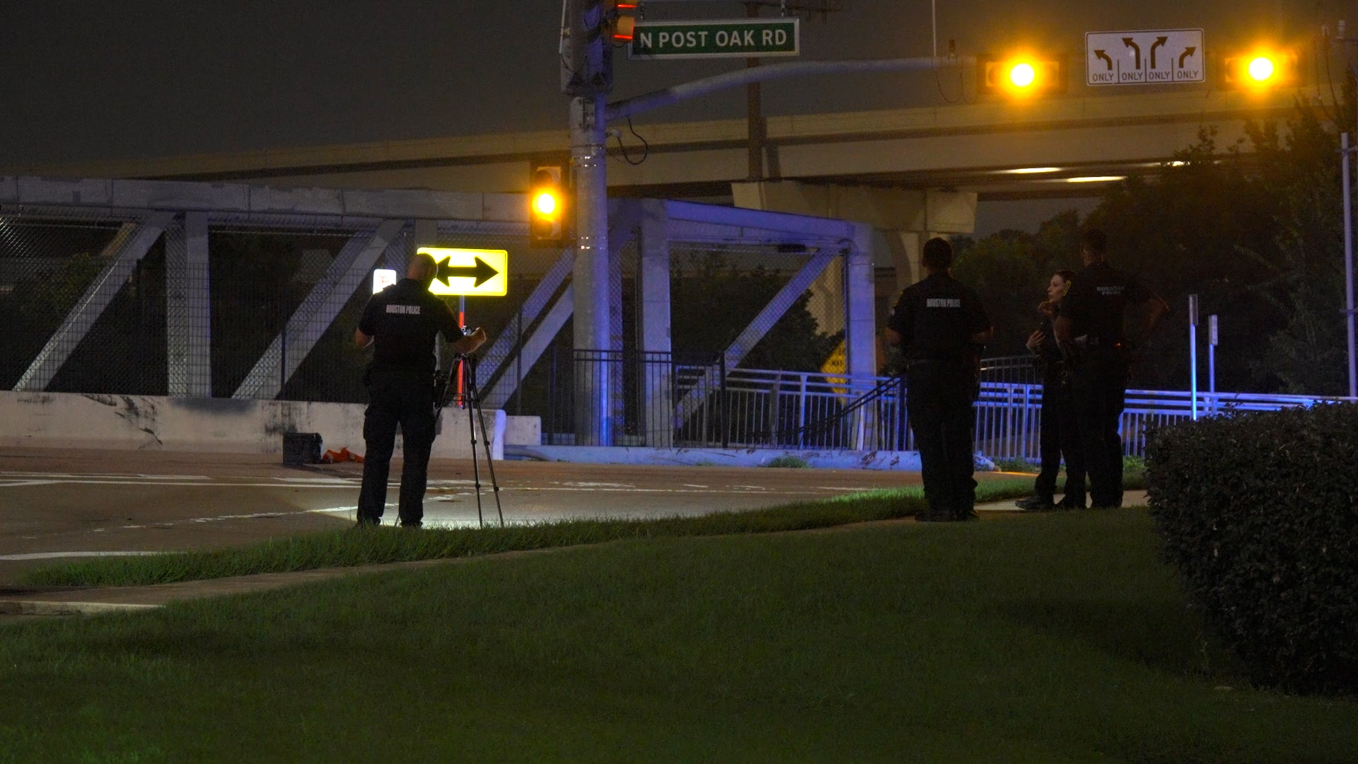 Nighttime scene with Houston police officers near a crosswalk and a tripod-mounted camera.