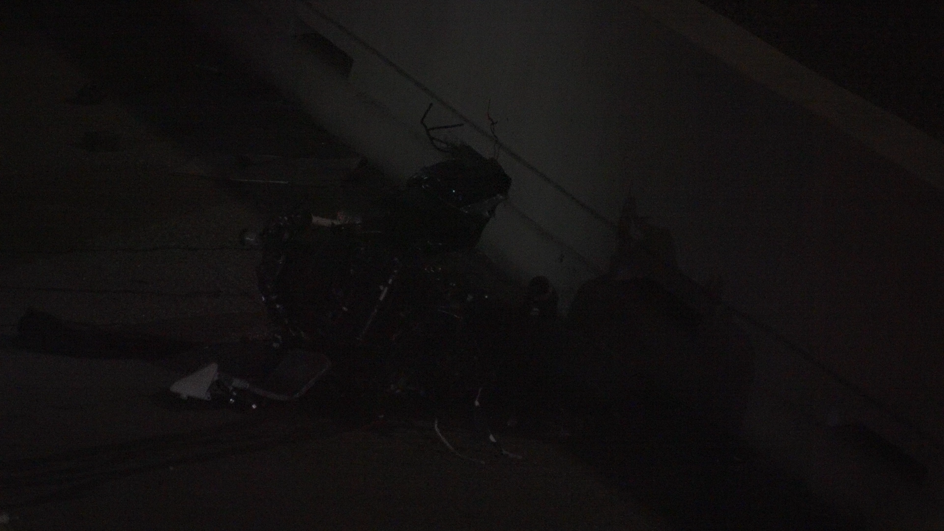 Dim, nighttime scene of charred debris and twisted metal on a snow-covered ground, barely visible in the dark.﻿